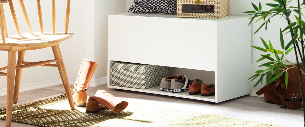 Ein Flur, das einen Schuhschrank mit einigen Schuhpaaren zeigt