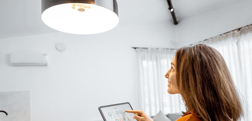 Frau steuert Deckenlampe mit Tablett