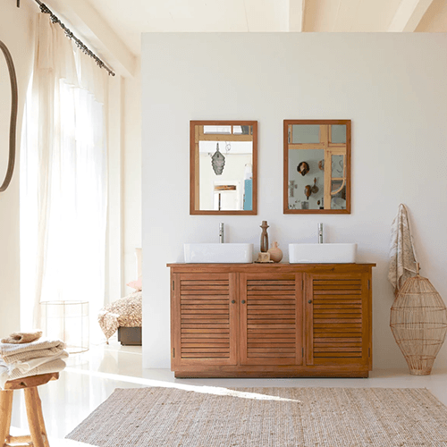 Ein Badezimmer, dass mit Holzmöbeln, zwei Wandspiegel und ein modernes Doppelwaschbecken ausgestattet ist. 