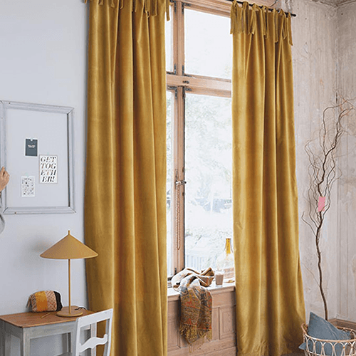 Gelbe Vorhänge an einem Fenster, neben einer gelben Tischlampe