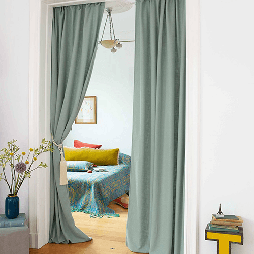 grünliche Gardine als Durchgang zu einem anderen Zimmer