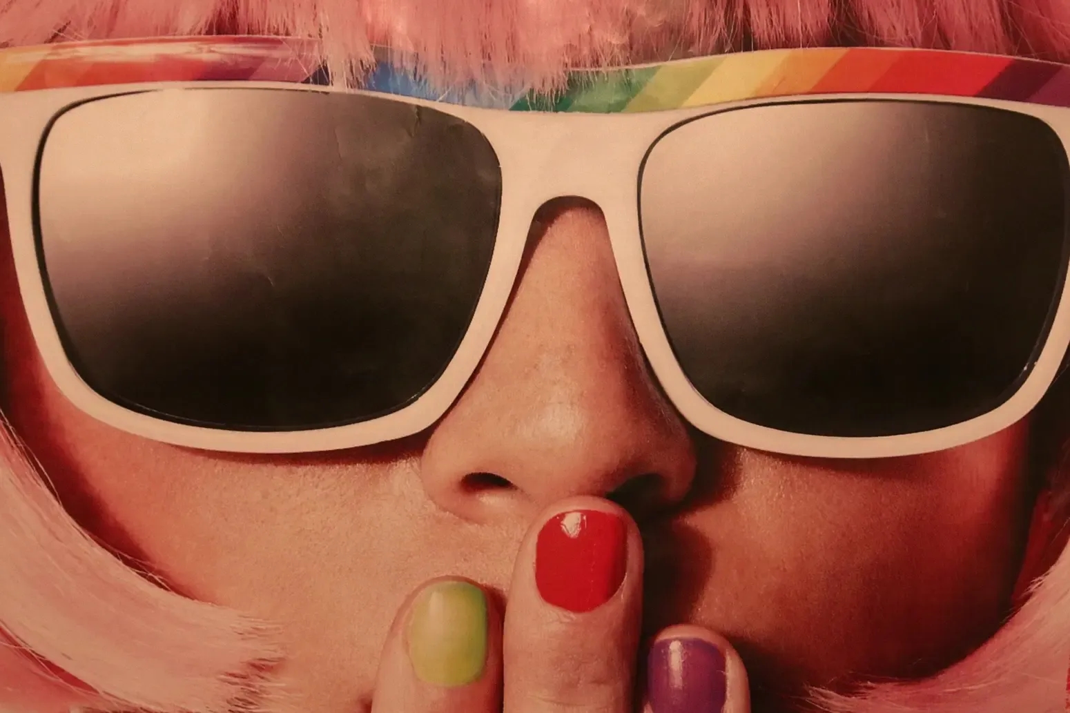 eine Frau mit einer bunten Sonnenbrille und bunten Fingernägeln