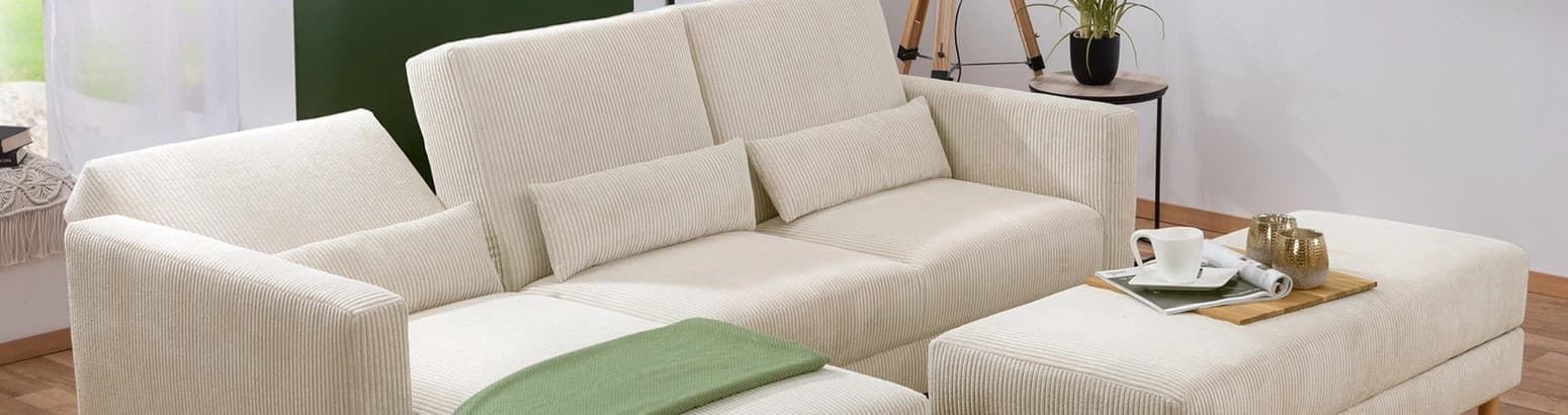 Ecksofa und Fußhocker aus Cordstoff in beige in einem Wohnzimmer dekoriert mit einer grünen Wolldecke