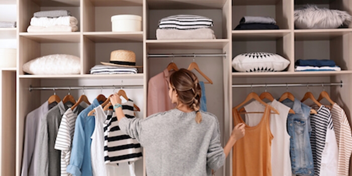 Frau vor Kleiderschrank mit Schubfächern und Kleiderstangen